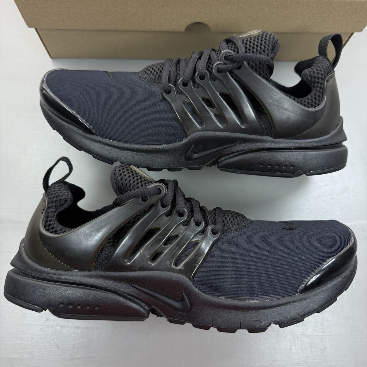 Nike Air Presto black trainers with logo detailing and breathable mesh upper.