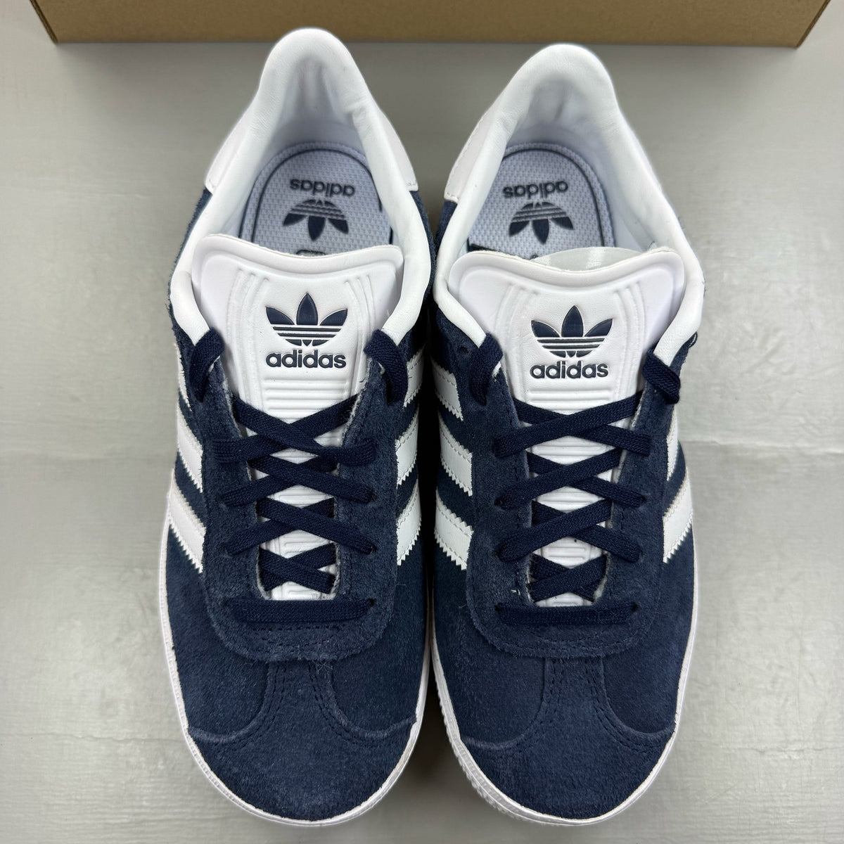 Adidas Gazelle blue trainers with white stripes and classic logo detail.