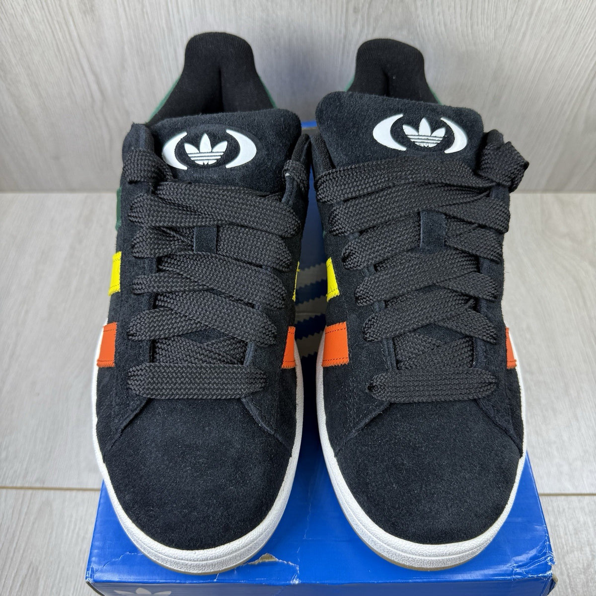 Adidas black trainers with yellow accents and classic three-stripe logo design.