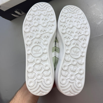 Adidas green deck shoes with white accents and logo detailing.