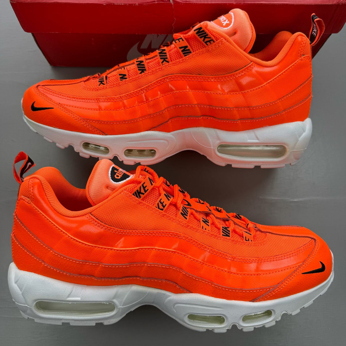 Nike Air Max 95 orange trainers with white overbranding and logo details.