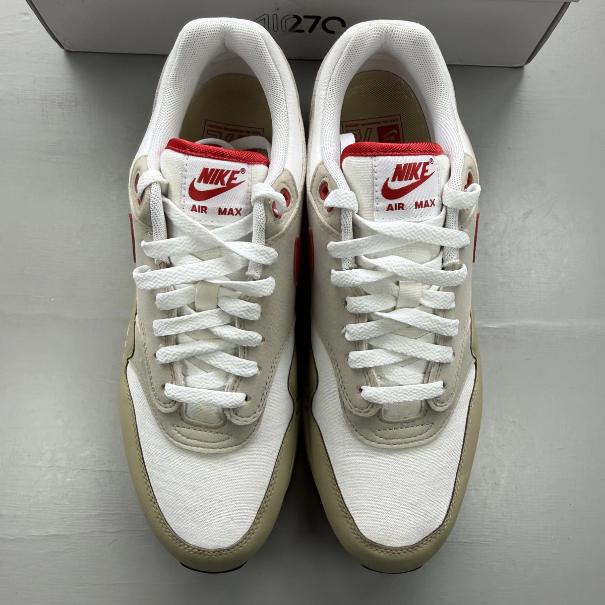 Nike Air Max 1 white trainers with red accents and classic logo detailing.