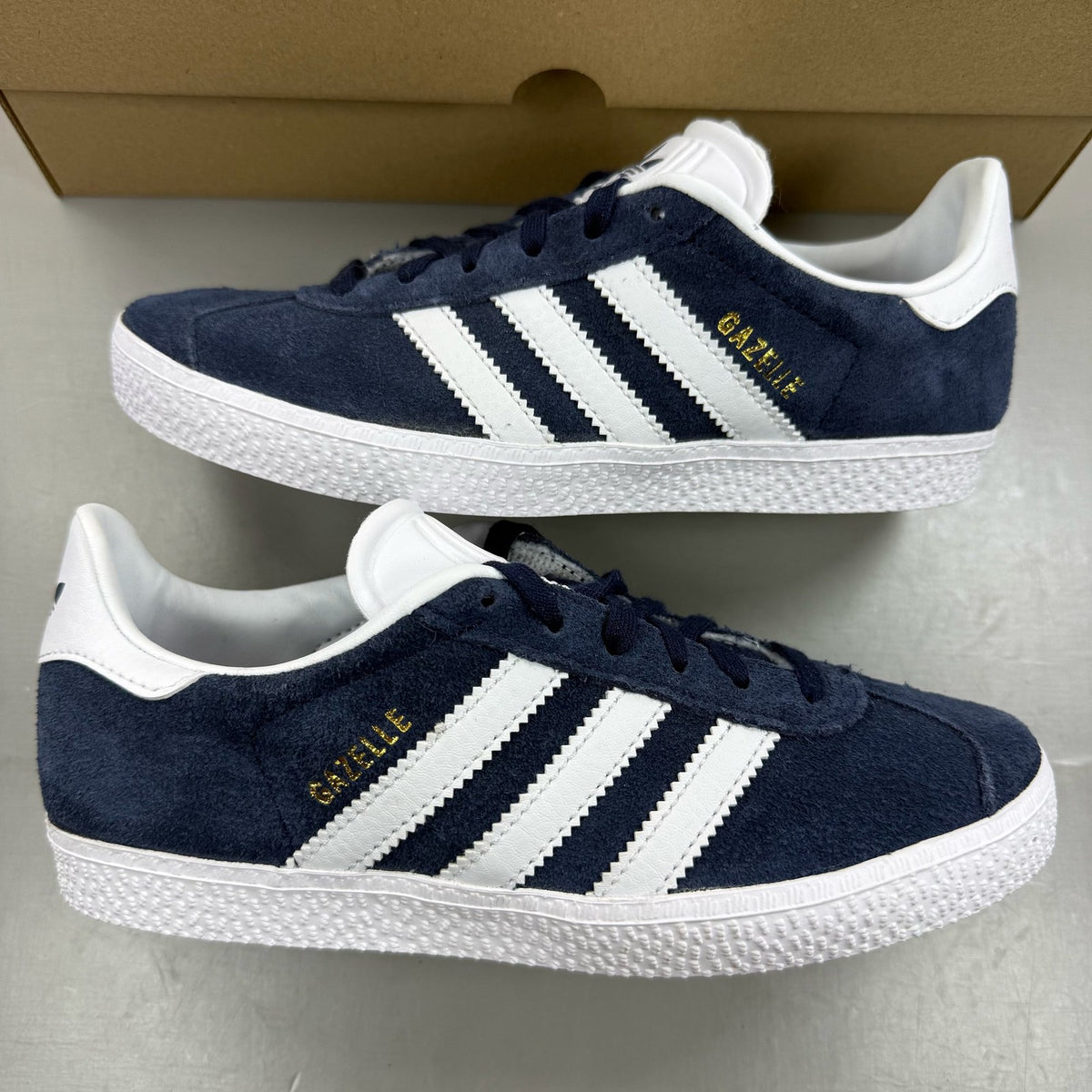 Adidas Gazelle blue trainers with white stripes and classic logo detail.
