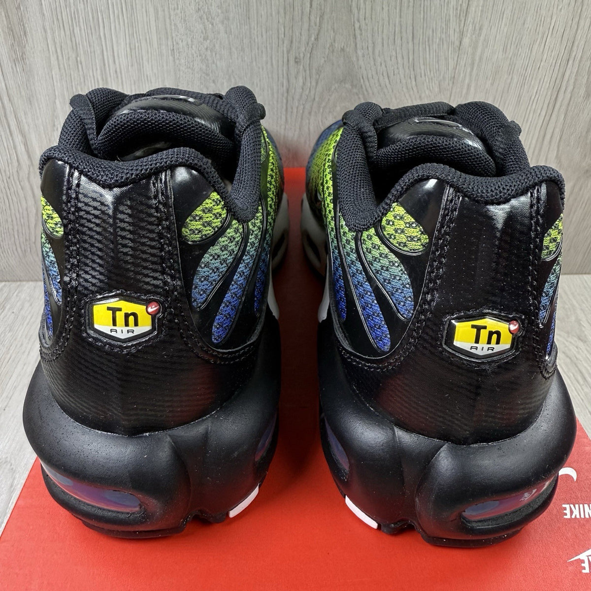 Nike Air Max Plus TN trainers black with racer blue and volt accents, mesh material.