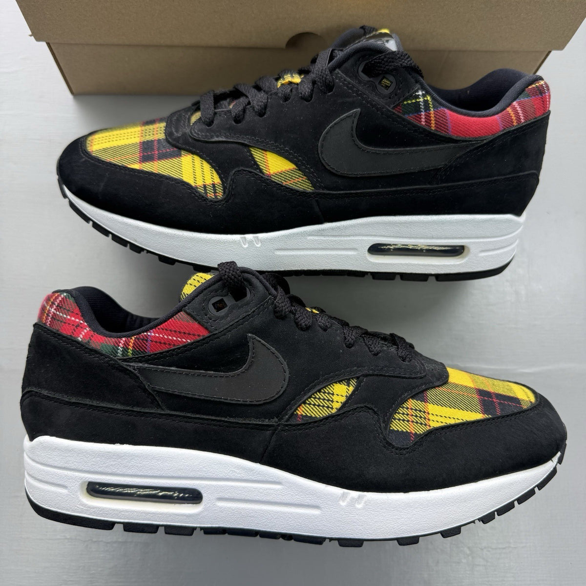 Nike Air Max 1 SE trainers black with tartan pattern and yellow accents.