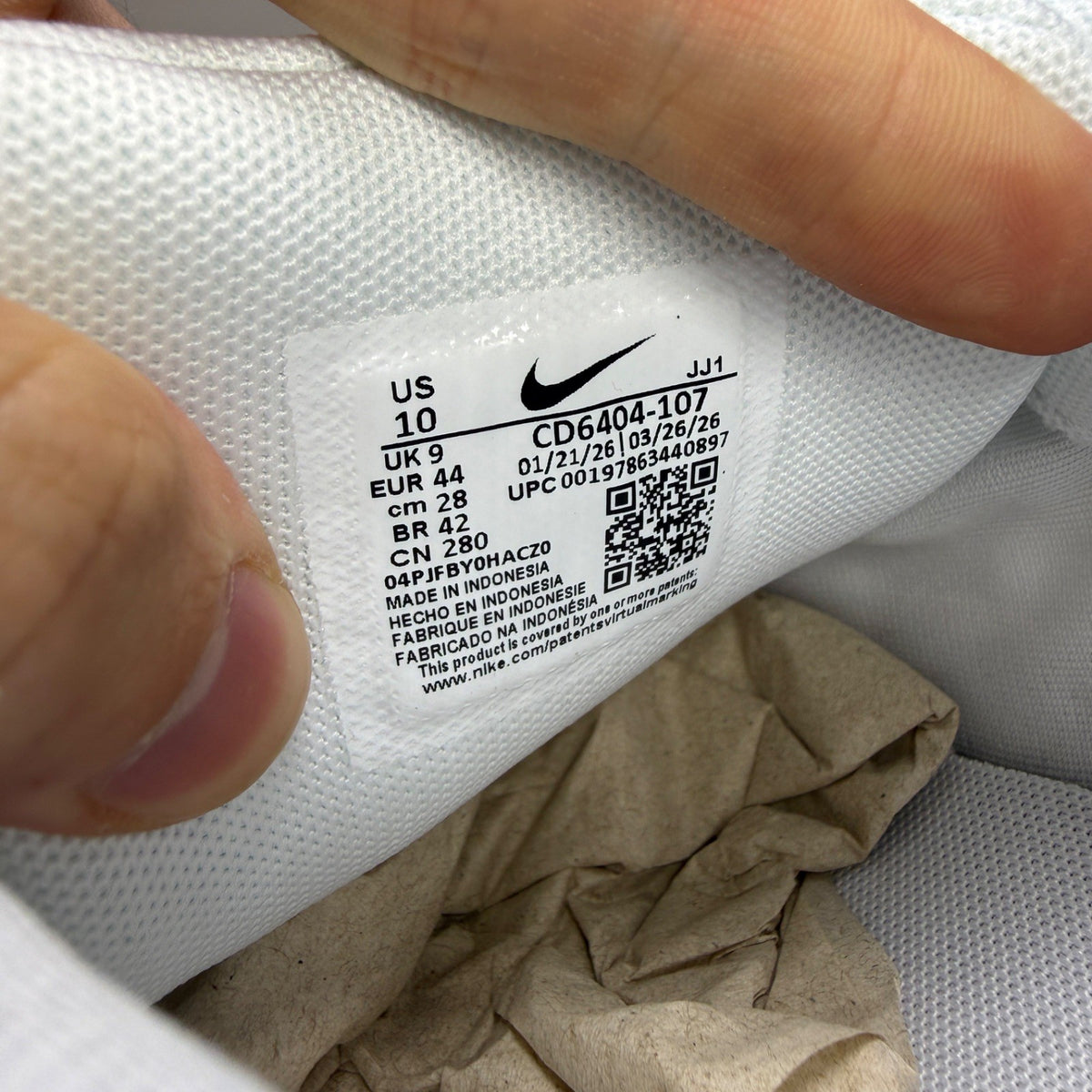 Nike white trainers with metallic silver accents and black detailing, featuring a sleek design.