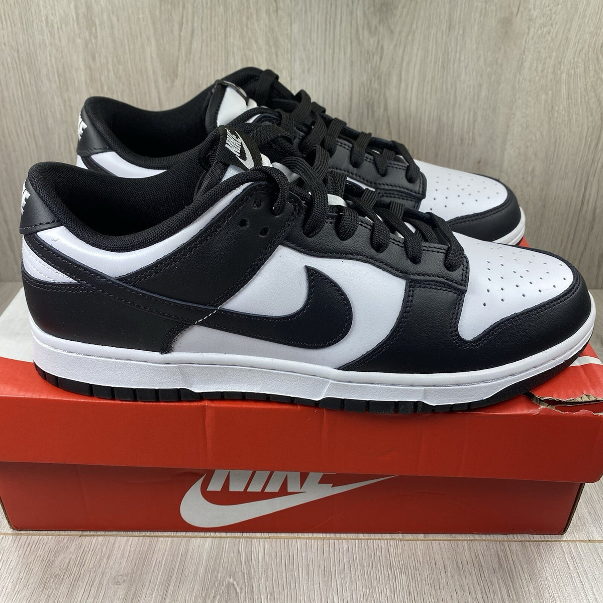 Nike Dunk Low trainers black and white with iconic swoosh logo and smooth leather upper.
