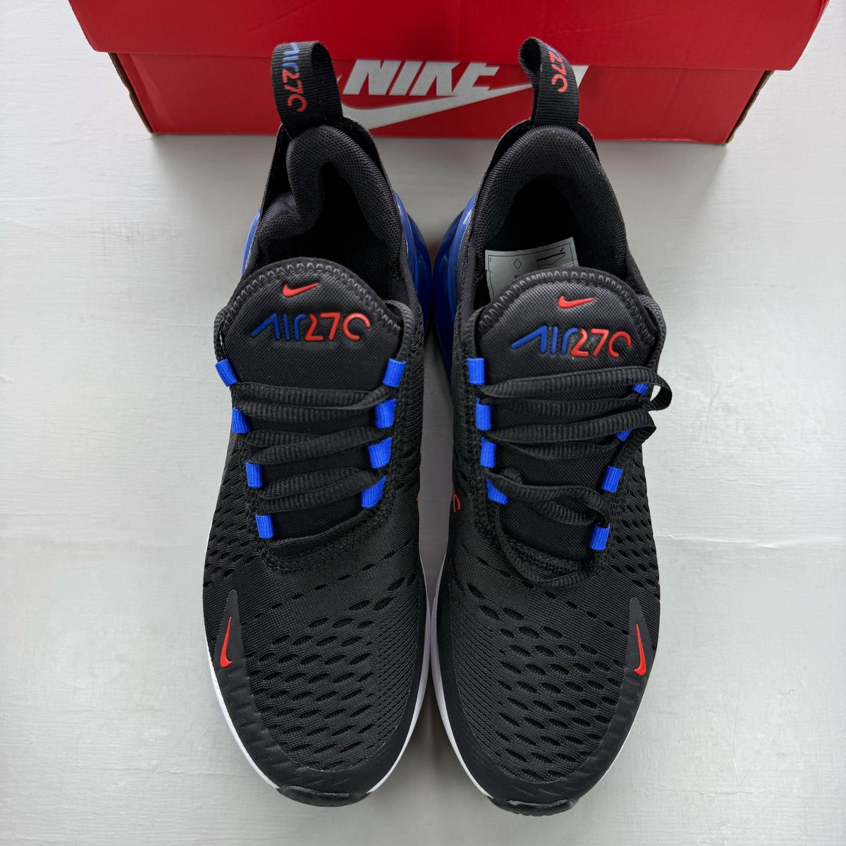 Nike black Air Max 270 trainers with blue accents and logo detail.