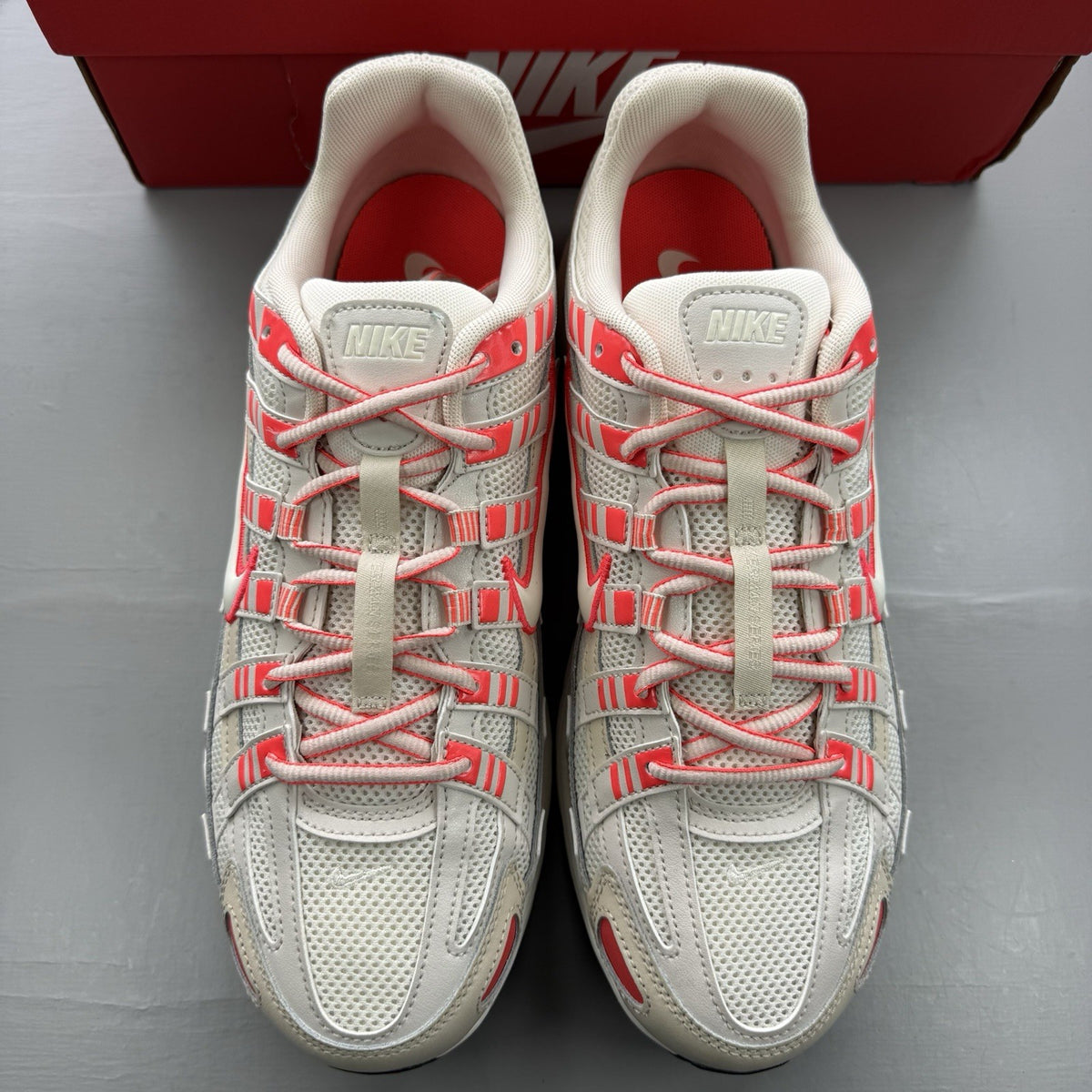 Nike white trainers with bright crimson red accents and soft pearl cream detailing.