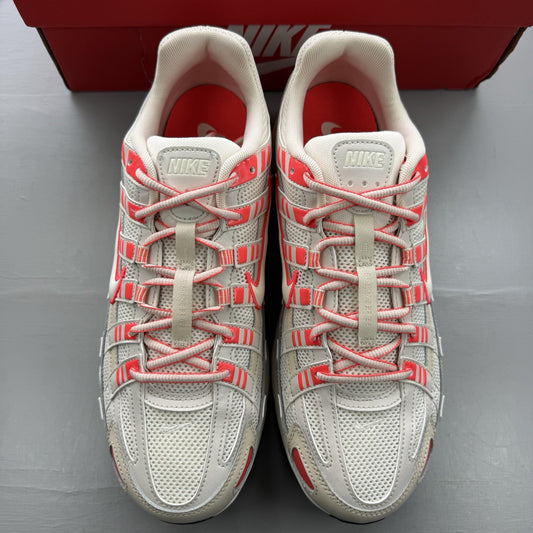 Nike white trainers with bright crimson red accents and soft pearl cream detailing.