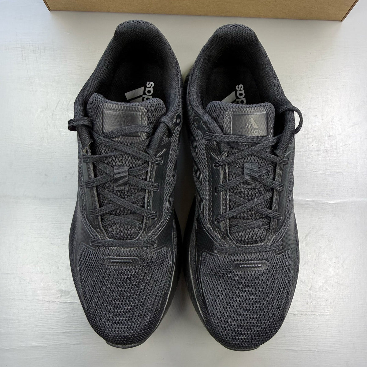 Adidas black trainers with signature three stripes and cushioned sole.