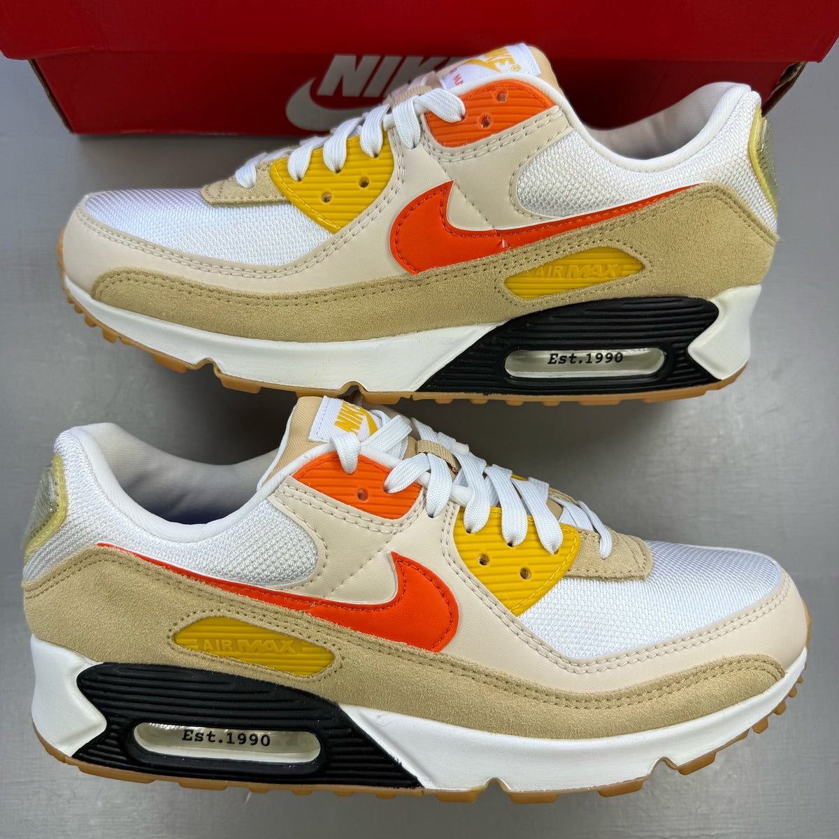 Nike Air Max 90 SE white trainers with orange accents and signature logo.