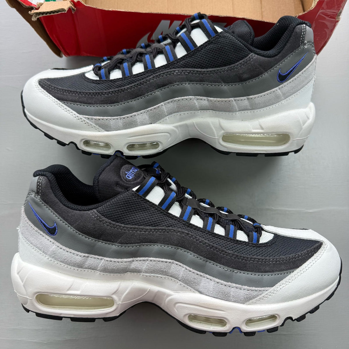 Nike black trainers with grey and white accents, featuring Air Max cushioning and logo.