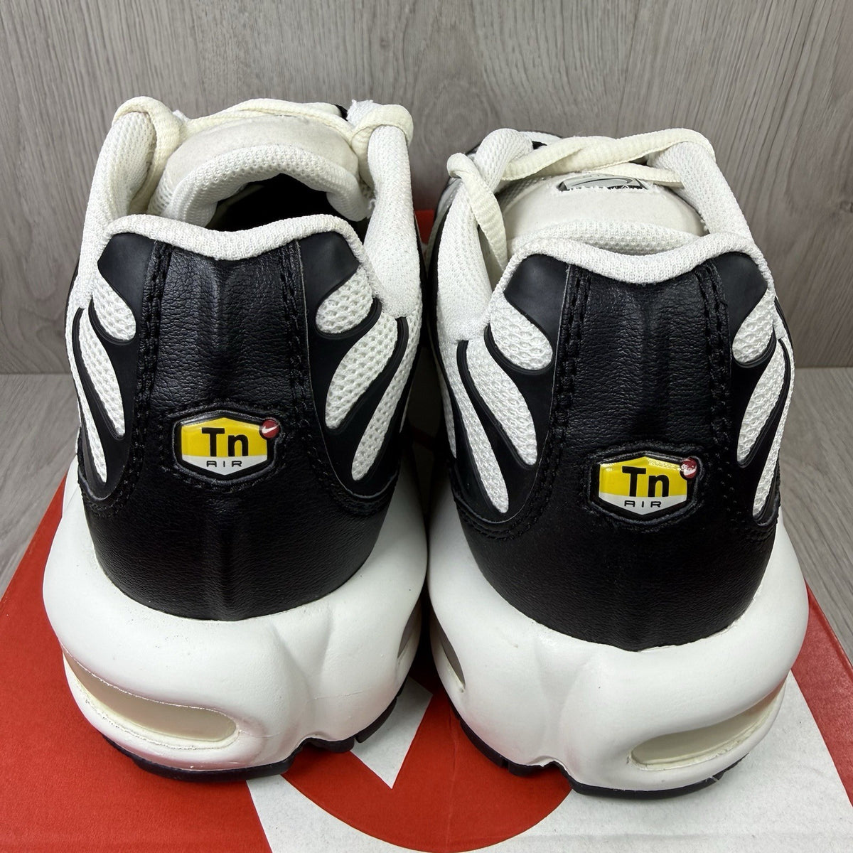 Nike Air Max Plus TN ESS trainers white with black accents and signature swoosh logo.