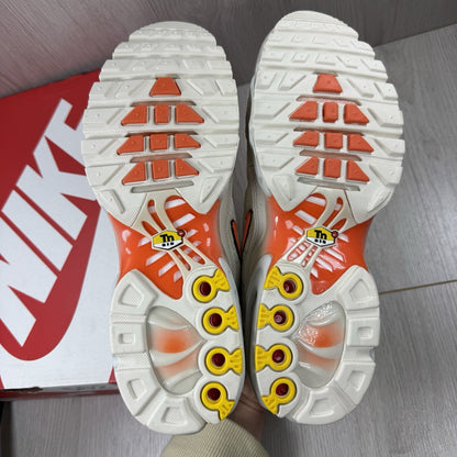 Nike Air Max Plus TN trainers in safety orange with distinctive wave pattern and logo.