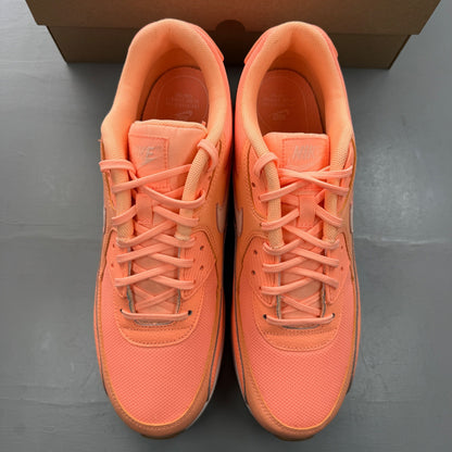 Nike Air Max 90 orange trainers with white and gum sole, featuring iconic logo.