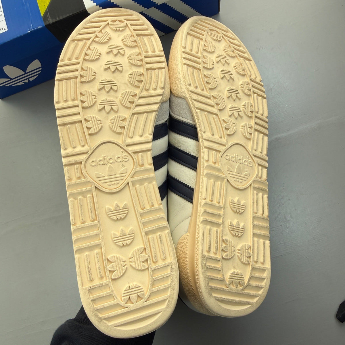 Adidas white trainers with navy accents and leather detailing, featuring iconic logo.