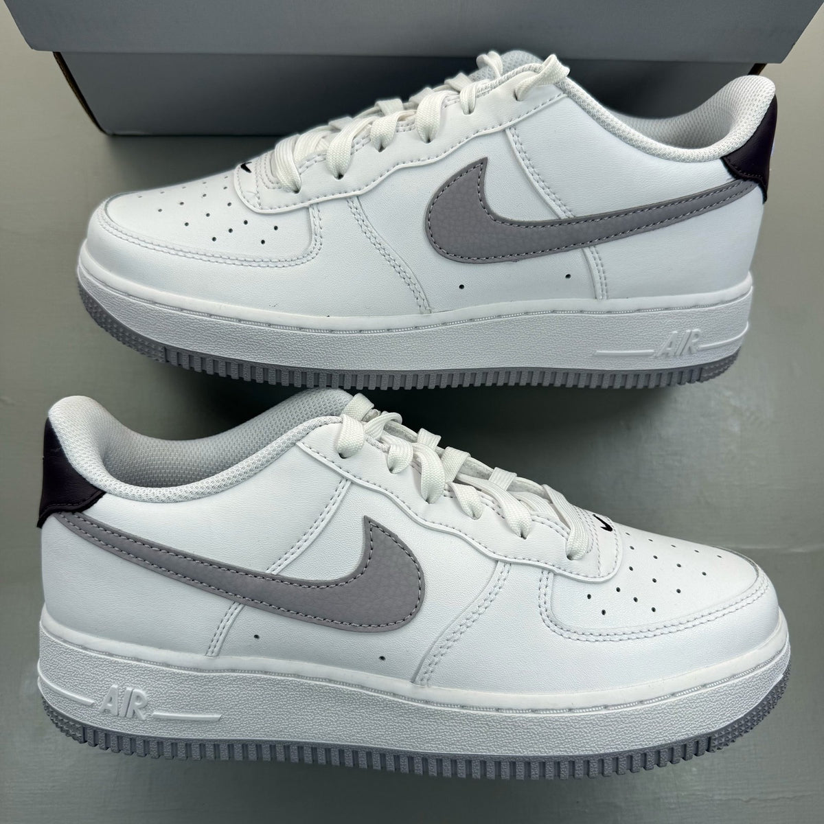 Nike Air Force 1 low white trainers with grey cement accents and logo detailing.