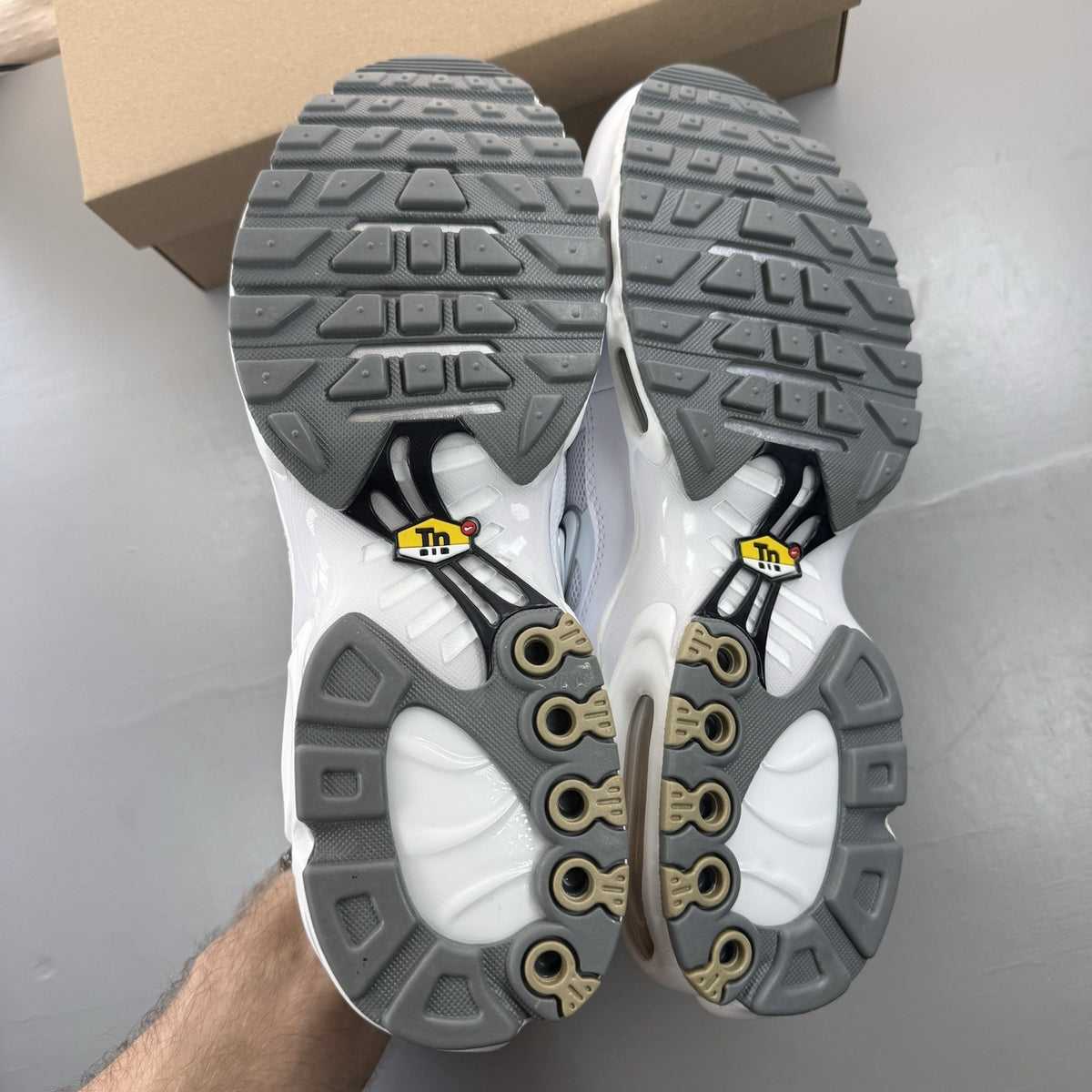 Nike Air Max Plus TN white trainers with grey accents and signature swoosh logo.