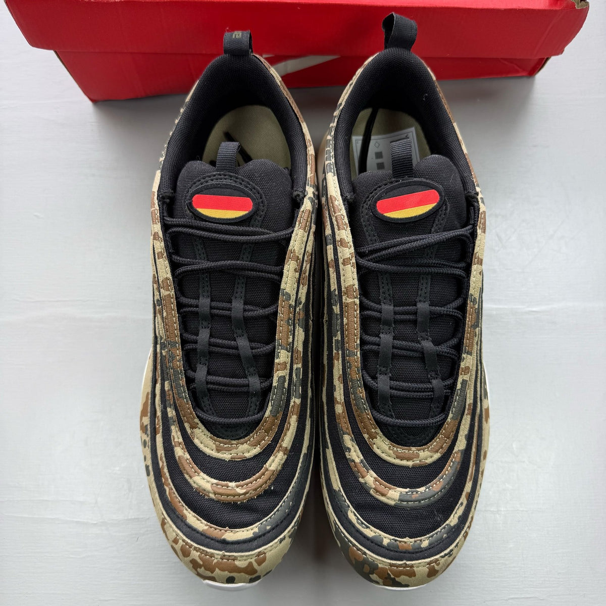 Nike black Air Max 97 trainers with country camo pattern and logo details.