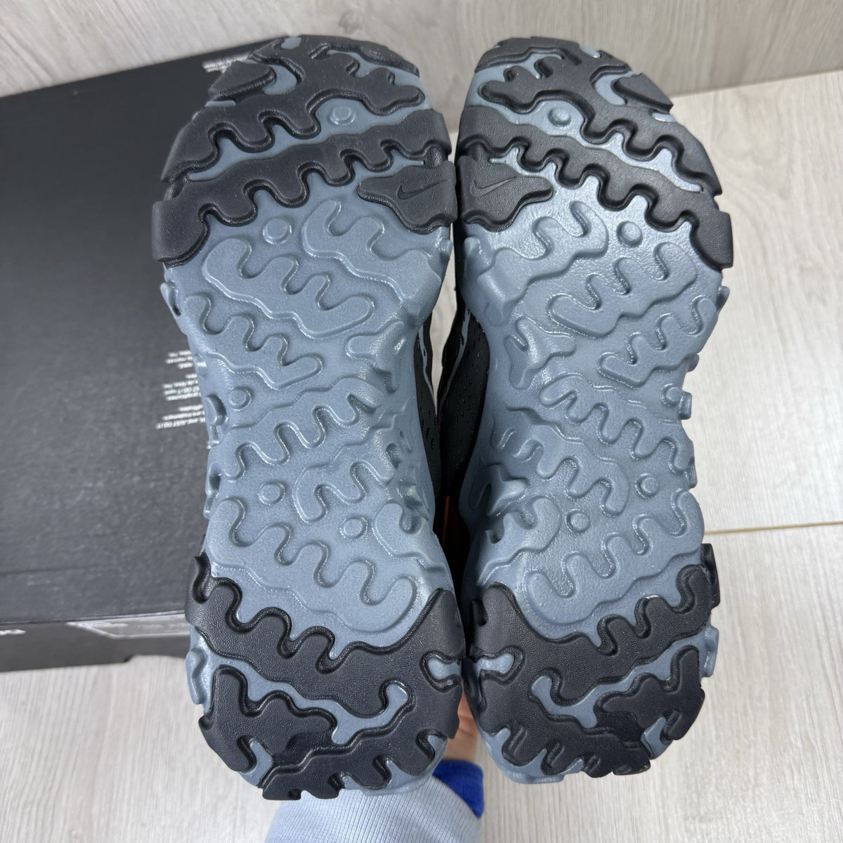 Nike React Vision black trainers with safety orange accents and unique design details.