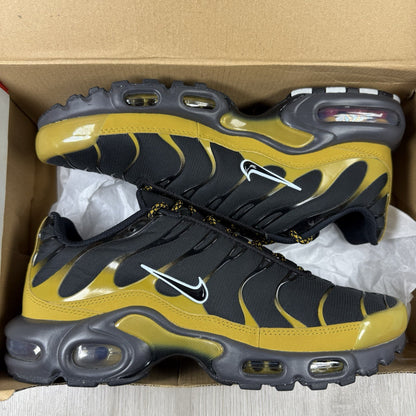 Nike Air Max Plus TN trainers black with gold accents and distinctive wavy pattern.