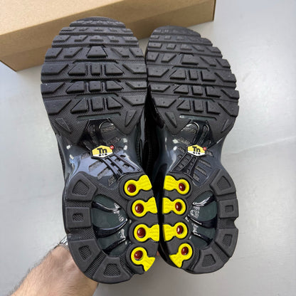 Nike Air Max Plus TN black trainers with dark smoke grey accents and logo detailing.