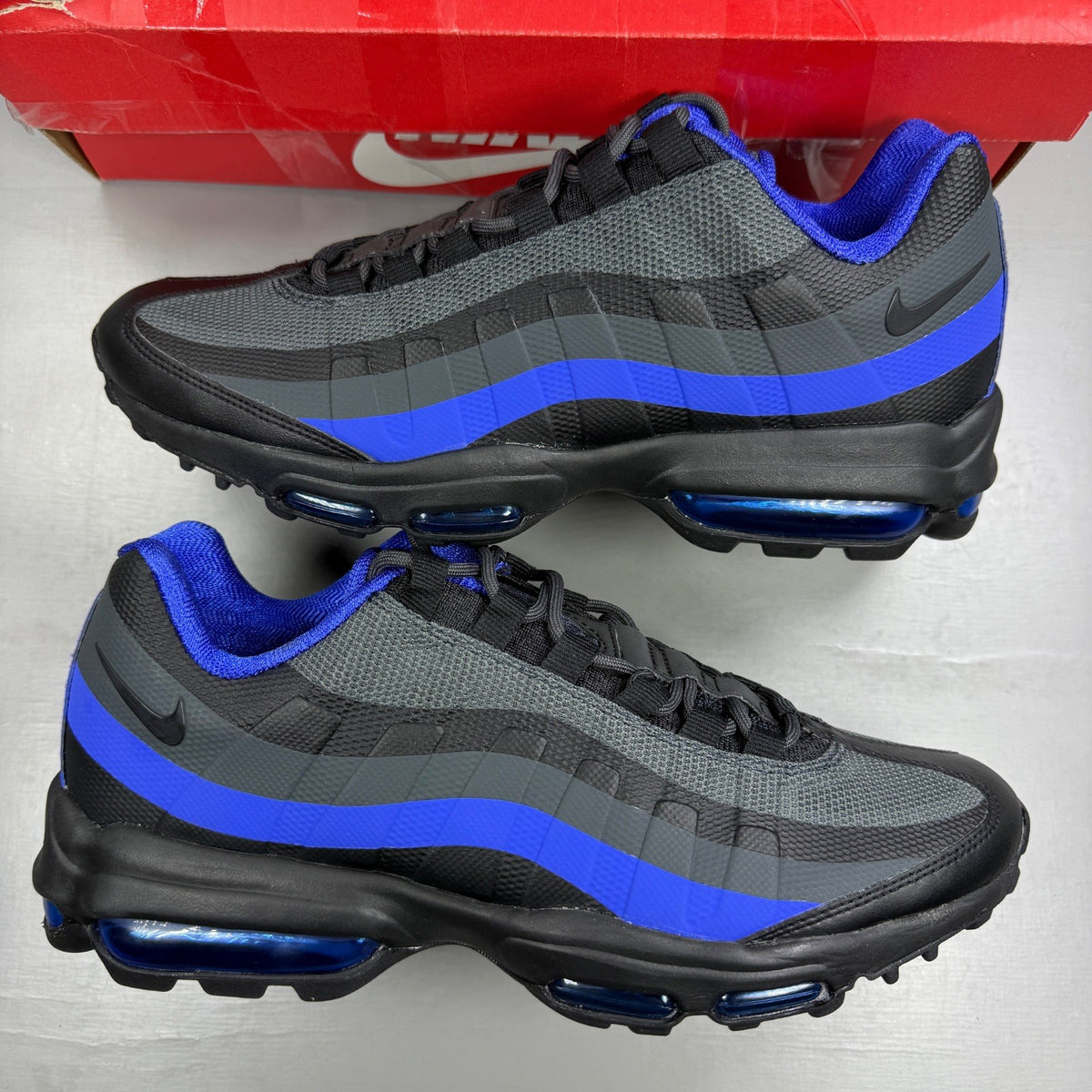 Nike Air Max 95 Ultra black trainers with blue accents and mesh upper.