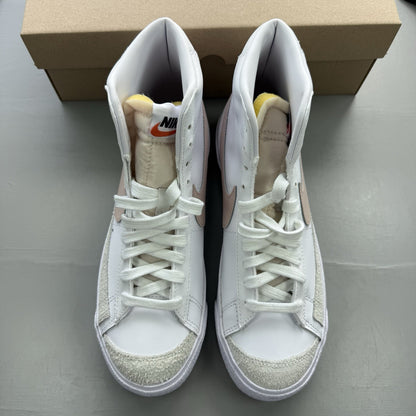 Nike Blazer Mid 77 white trainers with pink accents and retro logo design.