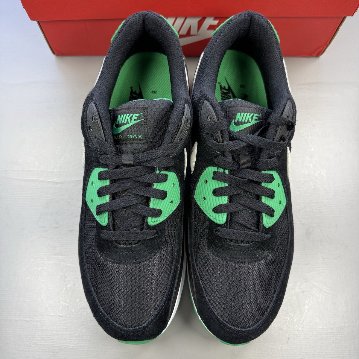 Nike Air Max 90 black trainers with stadium green accents and white sole.