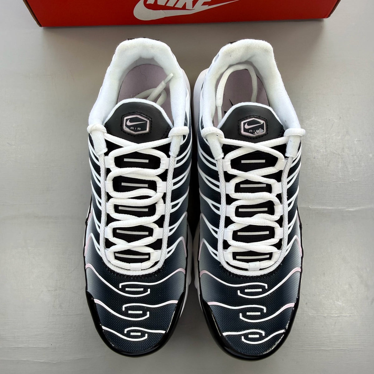 Nike trainers white with pink accents and black detailing, featuring Air Max cushioning.