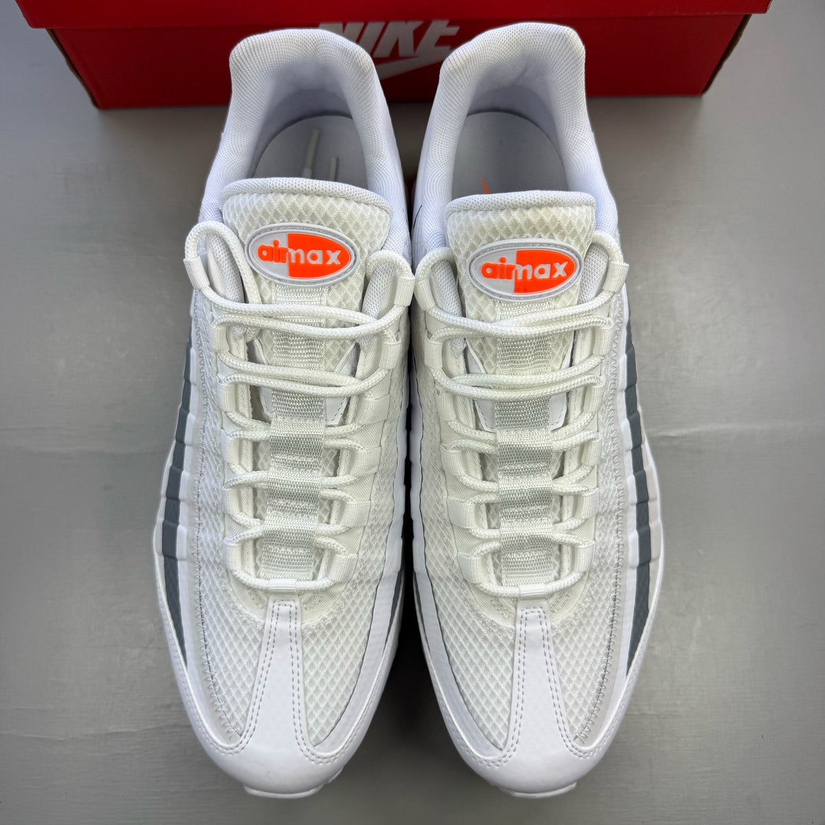Nike Air Max 95 white trainers with grey accents and distinctive air cushioning design.