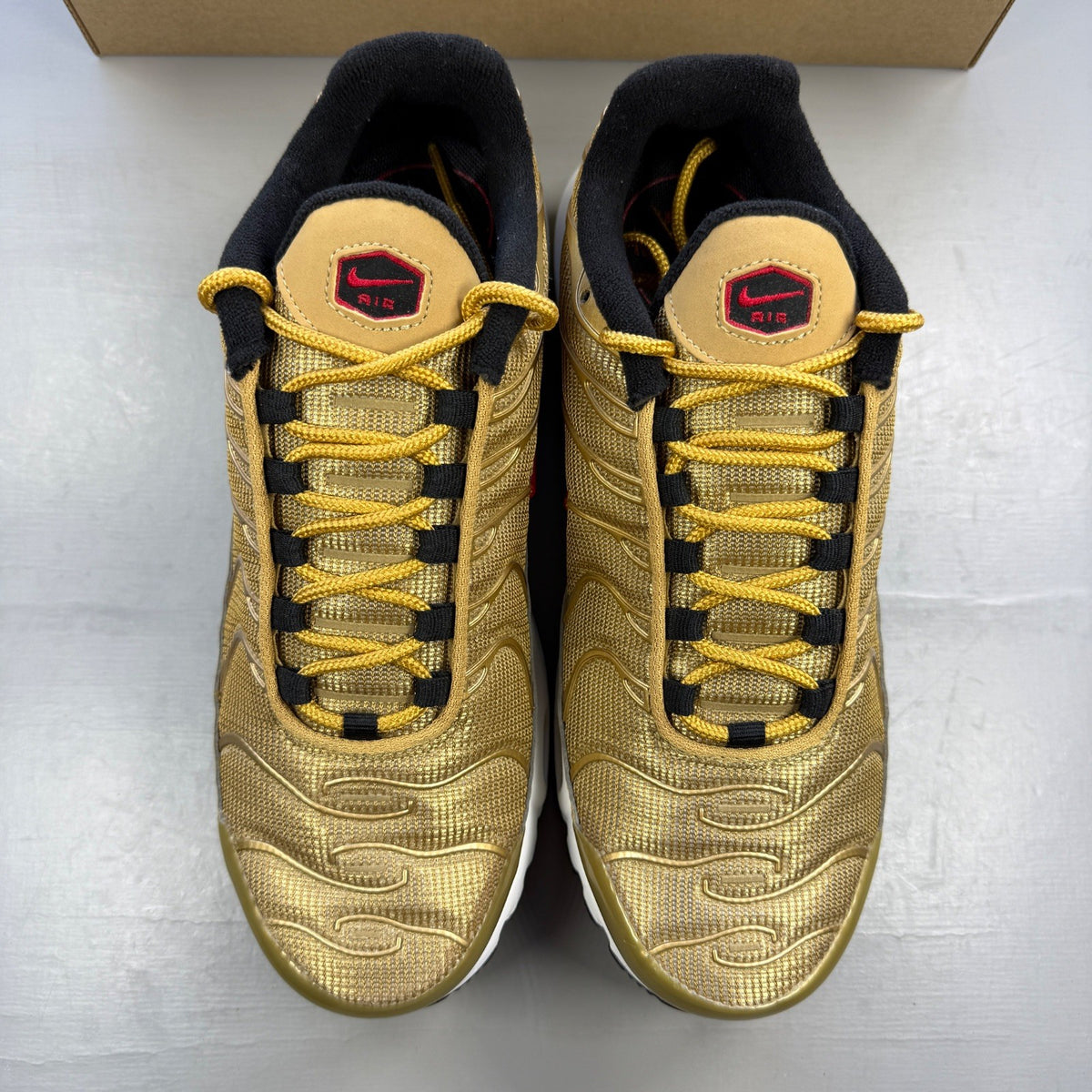 Nike gold trainers with metallic finish and distinctive Air Max Plus TN design.