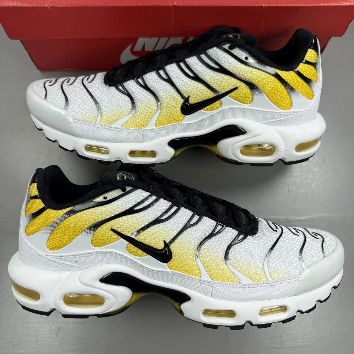 Nike Air Max Plus TN white with varsity maize yellow accents and signature logo.