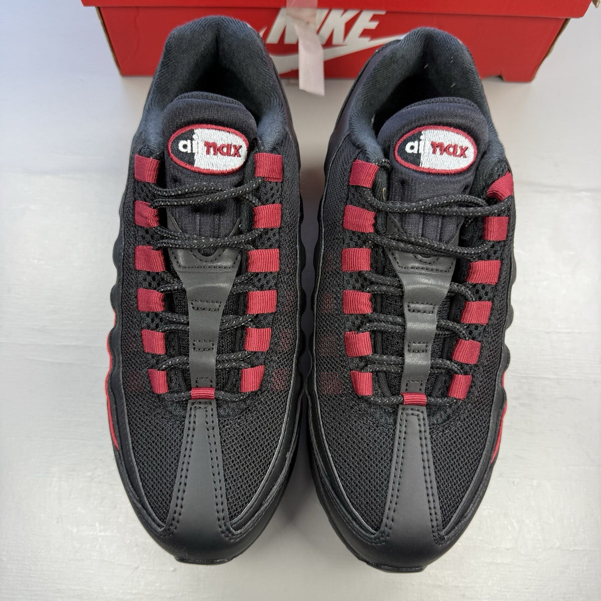 Nike Air Max 95 black trainers with crimson red accents and grey detailing.