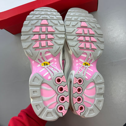 Nike athletic shoes white with pink accents and signature Air Max Plus design.