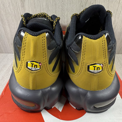 Nike Air Max Plus TN trainers black with gold accents and distinctive wavy pattern.