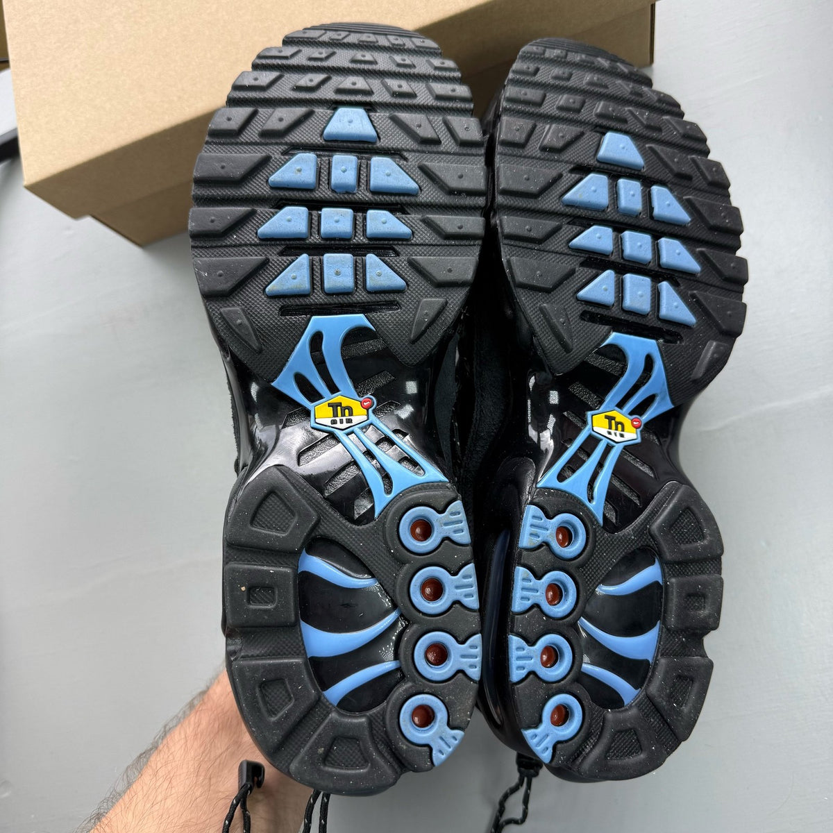 Nike Air Max Plus TN black trainers with distinctive wave pattern and cushioned sole.