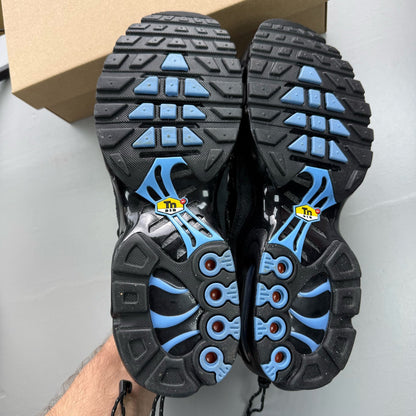 Nike Air Max Plus TN black trainers with distinctive wave pattern and cushioned sole.