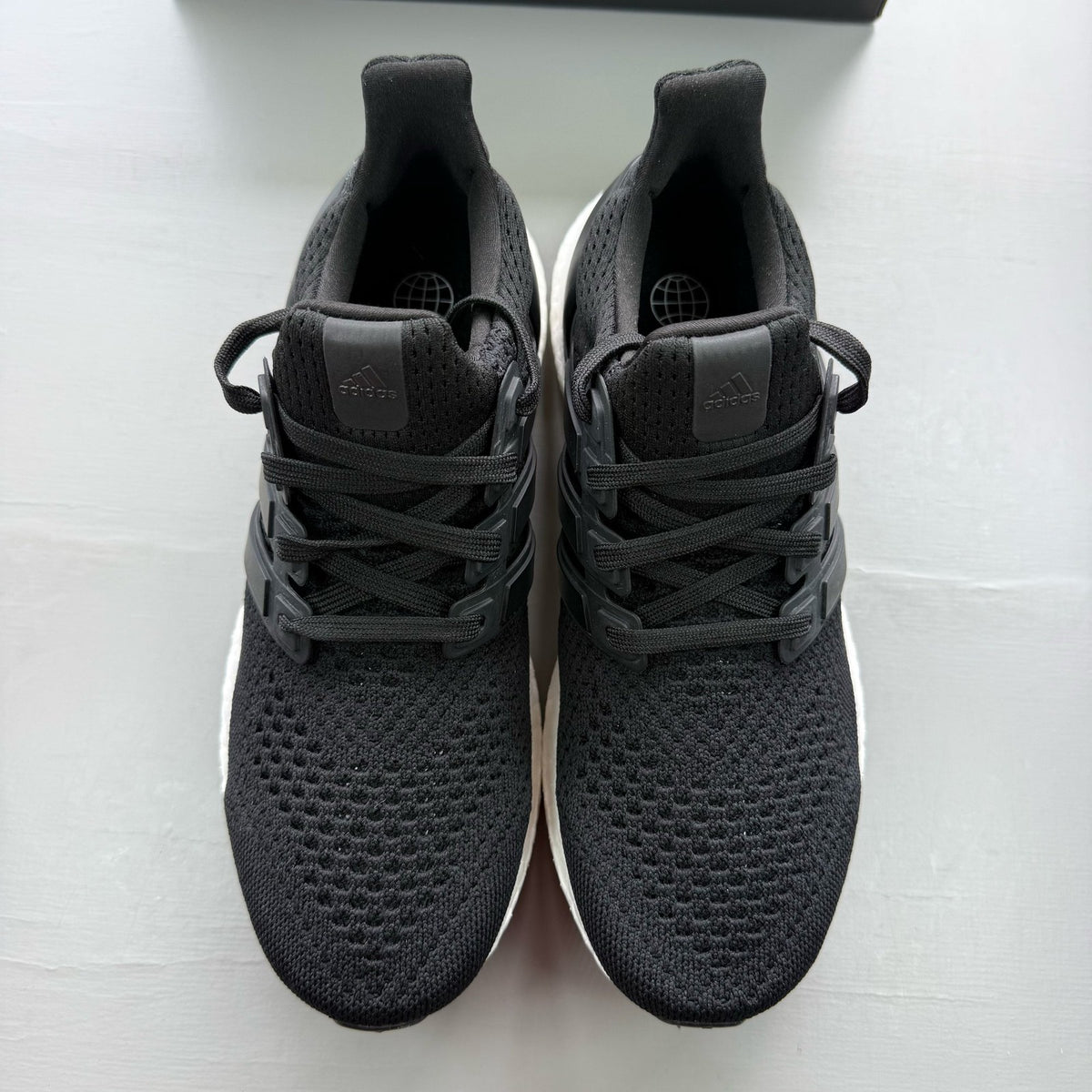 Adidas Ultraboost 1.0 black trainers with white accents and signature three-stripe logo.