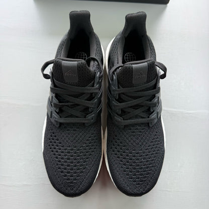Adidas Ultraboost 1.0 black trainers with white accents and signature three-stripe logo.