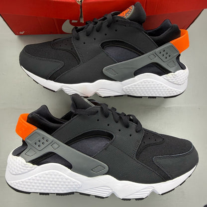 Nike black Air Huarache trainers with safety orange accents and white sole.