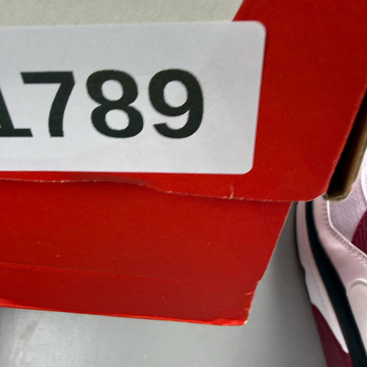 Nike Air Max 90 Recraft white trainers with maroon accents and logo detail.