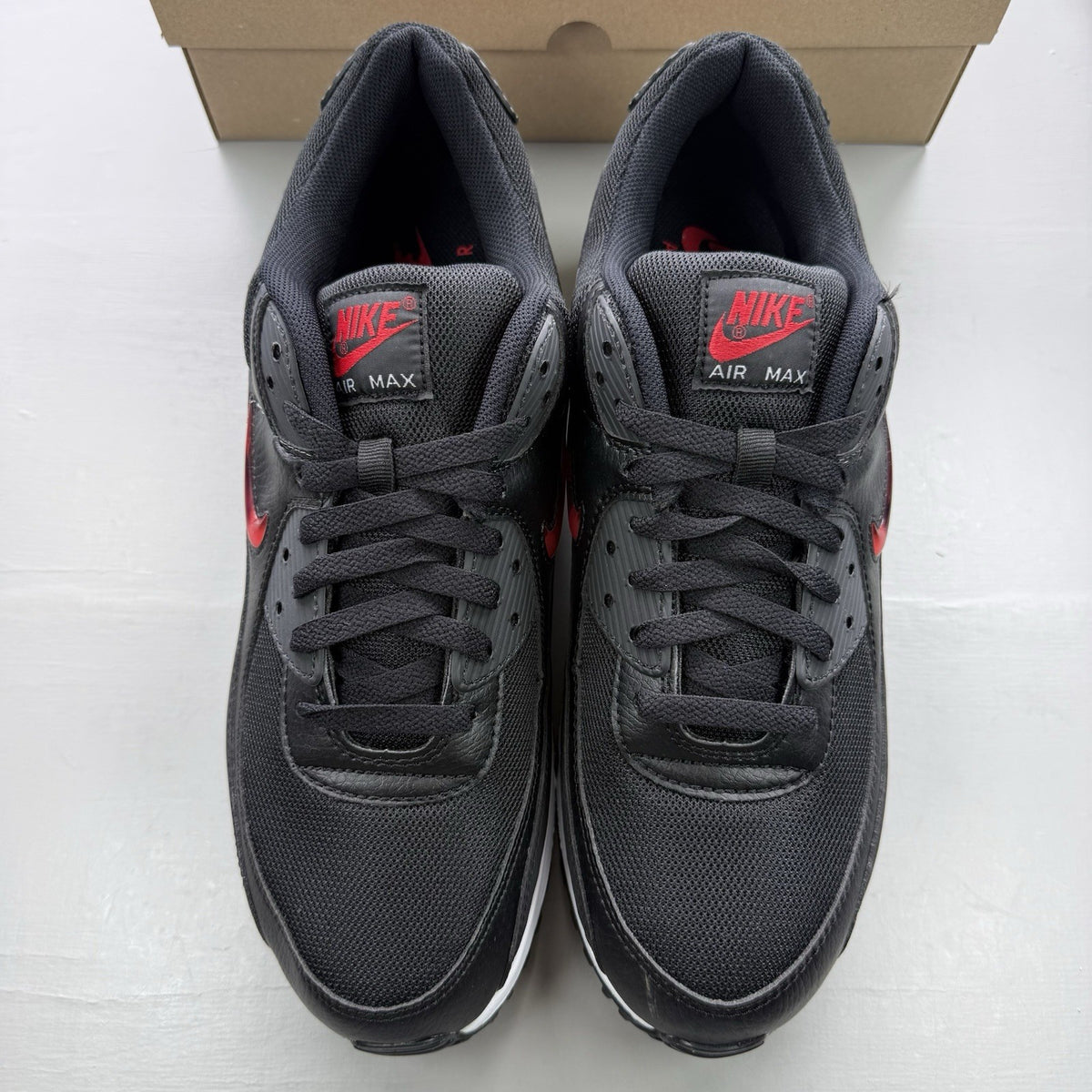 Nike Air Max 90 Jewel trainers black with red and white accents, featuring iconic logo.