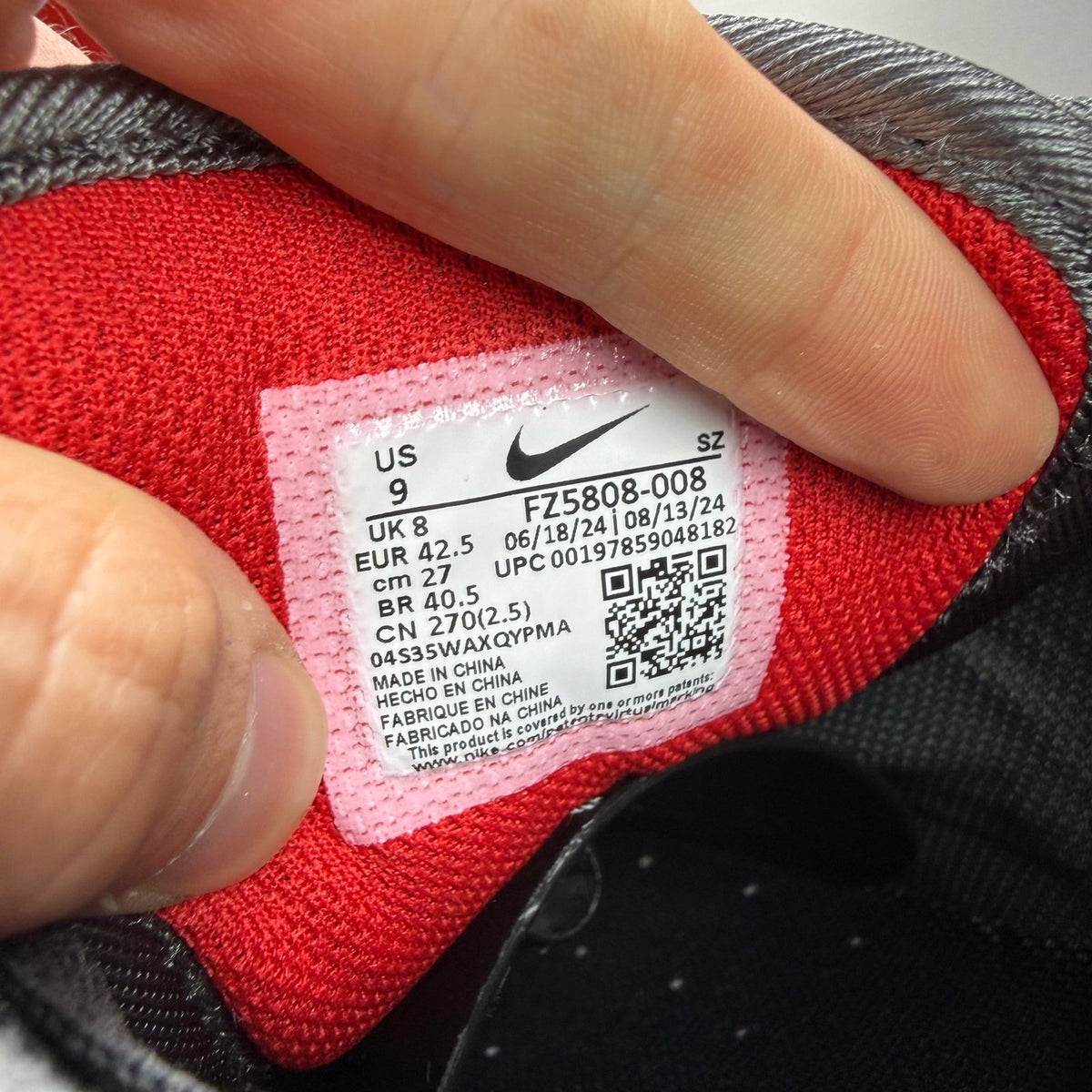 Nike black Air Max 1 trainers with red accents and logo detail.