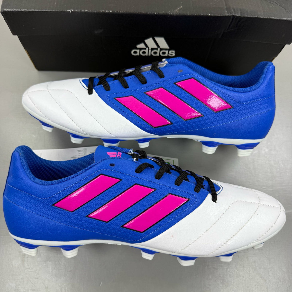 Adidas football boots white with blue and pink accents, featuring logo and textured material.