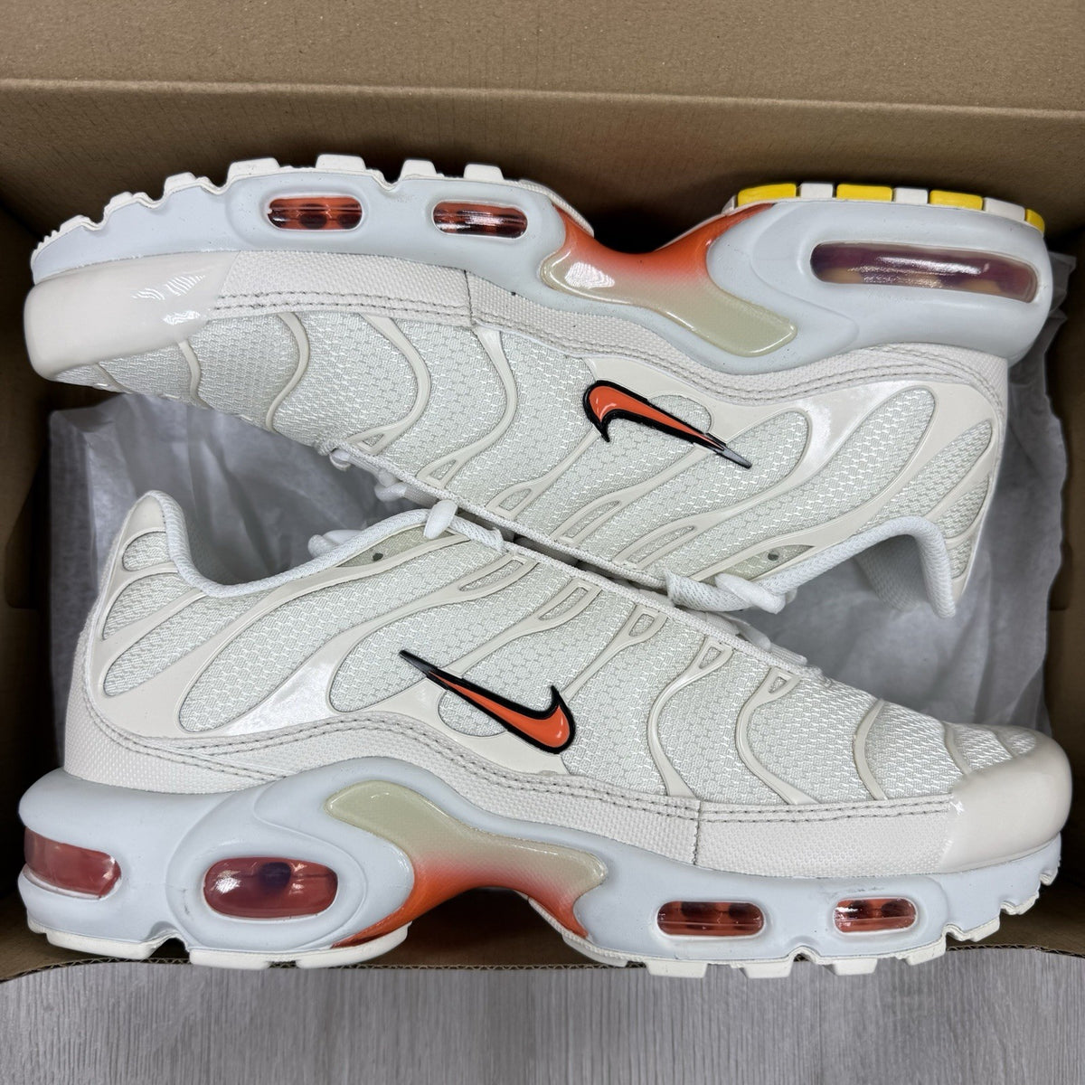 Nike Air Max Plus TN trainers in safety orange with distinctive wave pattern and logo.