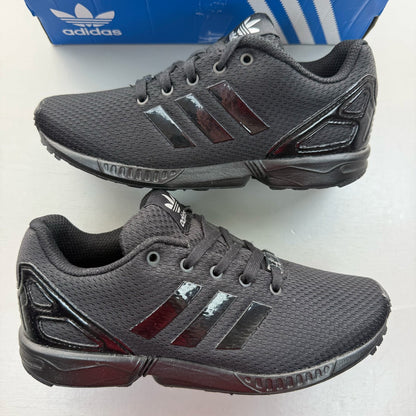 Adidas black trainers with sleek design and logo detail, perfect for kids.