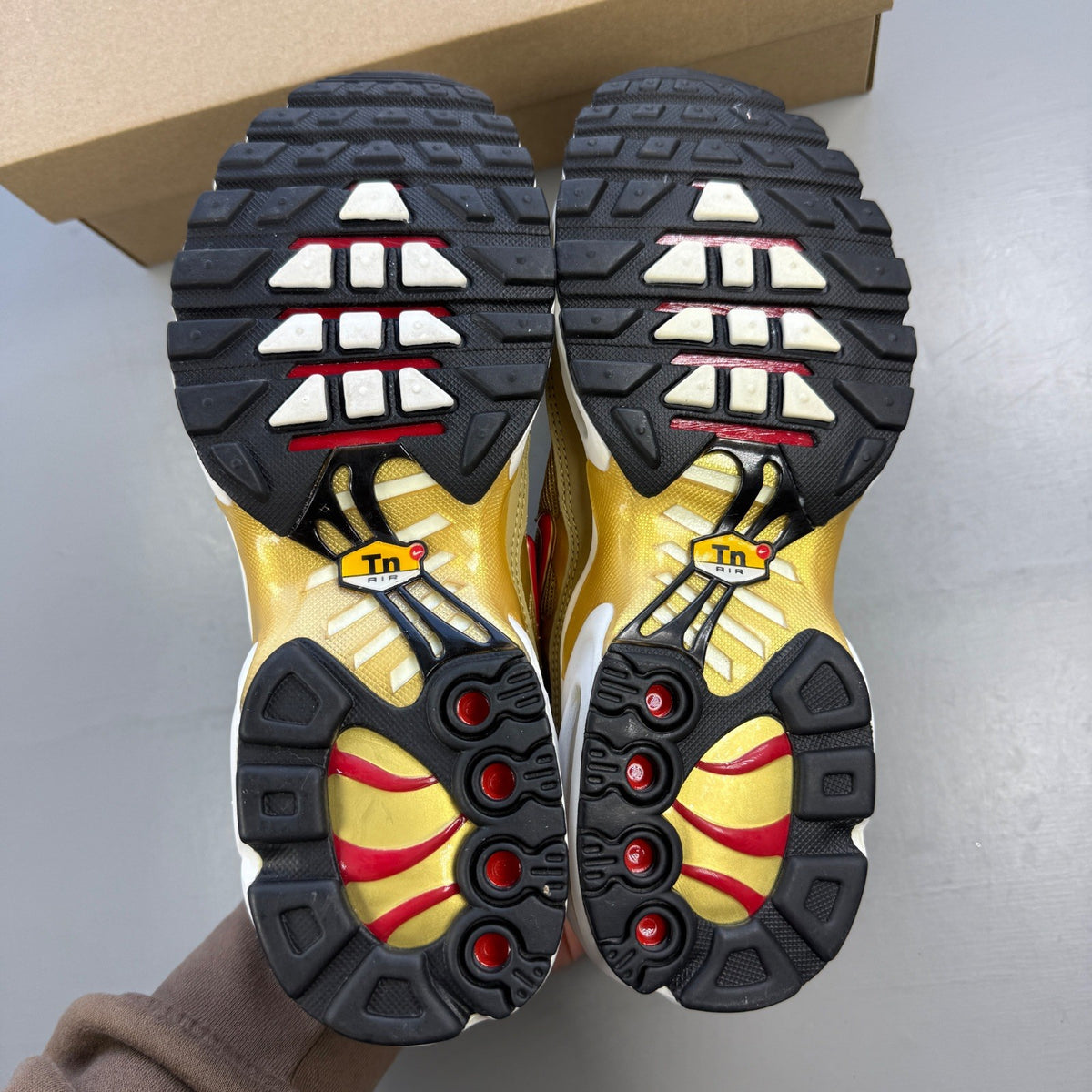 Nike gold trainers with metallic finish and distinctive Air Max Plus TN design.