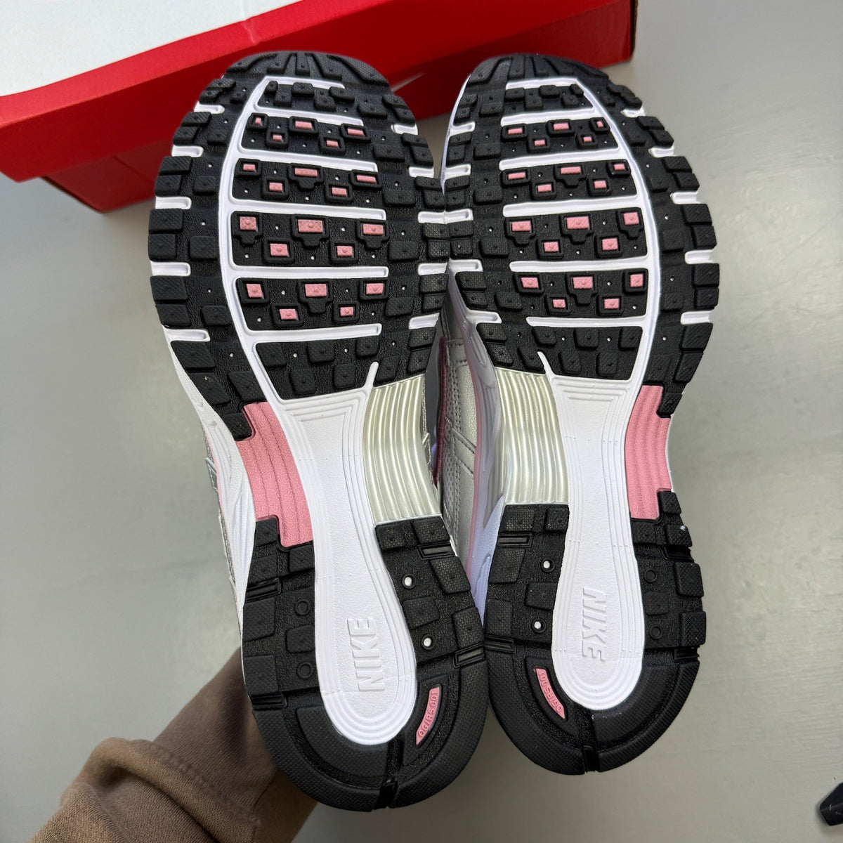Nike white trainers with elemental pink and silver accents, featuring logo details.